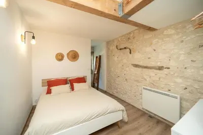 a bedroom with a bed and a stone wall at Maison de campagne 6 pers salle de jeux & pétanque in Cuq