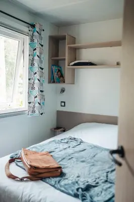 a bedroom with a bed and a window at Mobil Home XXL 4 chambres - Camping Le Barberousse in Gruissan