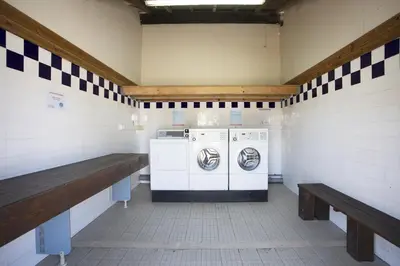 a utility room with two washing machines and a bench at Mobil Home XXL 4 chambres - Camping Le Barberousse in Gruissan