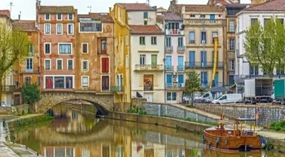 a group of buildings next to a river with a bridge at Studio mirabeau les halles 15m2 climatisation in Narbonne
