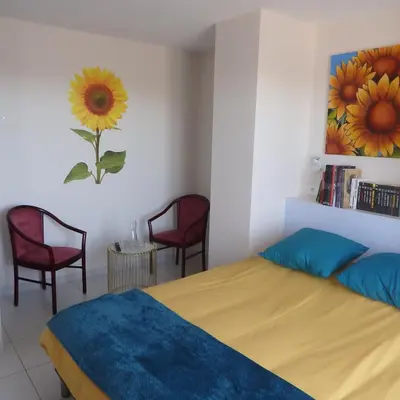 a bedroom with a bed and two chairs and a painting at L'oustal des Fontanilles in Castelnaudary