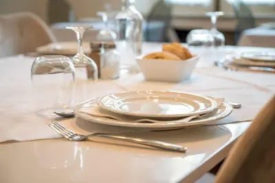 a table with plates and forks and a bowl of bread at La Grande Maison Mazamet in Mazamet