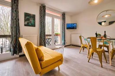 a living room with a yellow couch and a table at Tout confort ! Climatisation, Centre-ville, Parking, Terrasse, WiFi, Netflix in Carcassonne