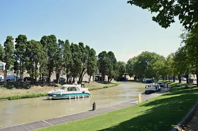 a boat is docked on a river with cars at Tout confort ! Climatisation, Centre-ville, Parking, Terrasse, WiFi, Netflix in Carcassonne