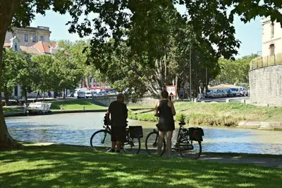 two people standing next to their bikes next to a river at Tout confort ! Climatisation, Centre-ville, Parking, Terrasse, WiFi, Netflix in Carcassonne
