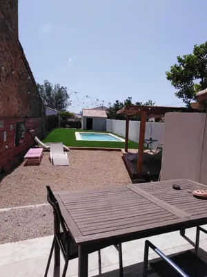 a wooden table and chairs in a backyard with a pool at maison a bizanet avec piscine in Bizanet
