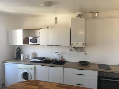 a kitchen with white cabinets and a sink and a dishwasher at Location de Chambres, Séjour près des Grands Buffets Narbonne in Narbonne