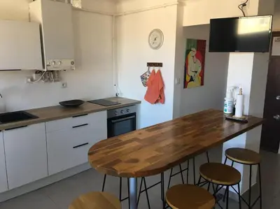 a kitchen with a wooden table and some stools at Location de Chambres, Séjour près des Grands Buffets Narbonne in Narbonne