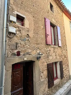a stone building with a door and two windows at Chez Nath et Oli in Caunes-Minervois