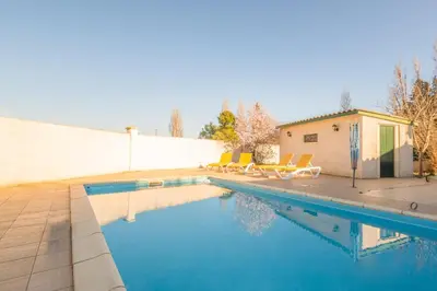 a swimming pool with chairs next to a wall at Maison des papillons in Ouveillan