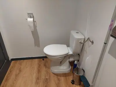 a white toilet in a bathroom with a wooden floor at bel appart T2 confortable en plein coeur de Sigean in Sigean