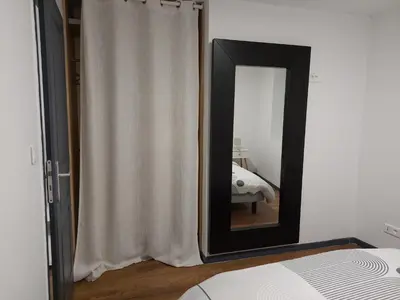 a mirror in a bedroom with a white curtain at bel appart T2 confortable en plein coeur de Sigean in Sigean