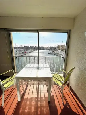 a table and chairs on a balcony with a view of a harbor at Idéal couple avec vue sur le PORT DE GRUISSAN 4CHE24 in Gruissan
