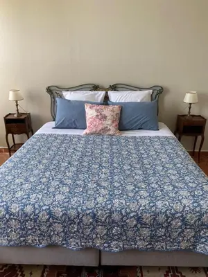 a bed with a blue comforter and pillows at Le Relais d'Affiac in Peyriac-Minervois