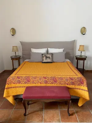 a bedroom with a bed with an orange bedspread at Le Relais d'Affiac in Peyriac-Minervois