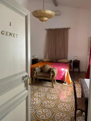 a bedroom with a bed and a chair and a door at Le Relais d'Affiac in Peyriac-Minervois
