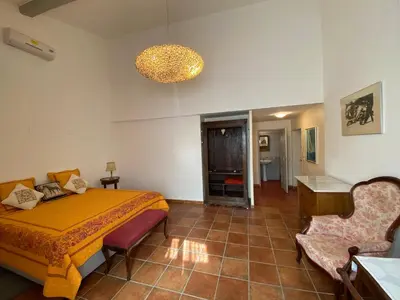 a bedroom with a bed and a chair and a chandelier at Le Relais d'Affiac in Peyriac-Minervois