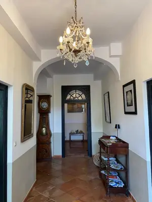 a hallway with a clock and a chandelier at Le Relais d'Affiac in Peyriac-Minervois
