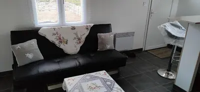 a black leather couch in a living room with pillows at La maisonnette du jardin Narbonne in Narbonne