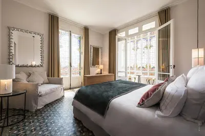 a bedroom with a large bed and a couch at Hôtel Le Mosaïque in Narbonne