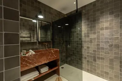 a bathroom with a sink and a shower with brown tiles at Hôtel Le Mosaïque in Narbonne