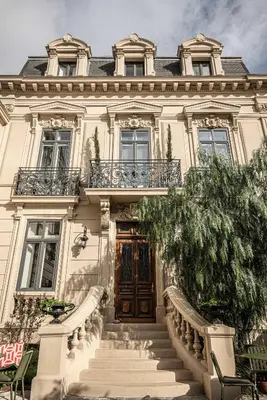 a large white house with stairs leading to a door at Hôtel Le Mosaïque in Narbonne