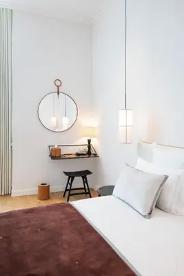 a bedroom with a white bed and a table at Hôtel Le Mosaïque in Narbonne