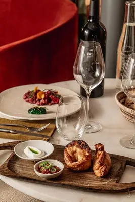 a table with a plate of food and wine glasses at Hôtel Le Mosaïque in Narbonne