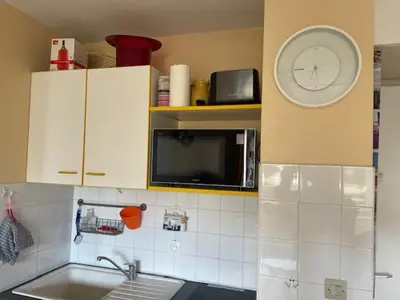 a kitchen with a clock on the wall above a sink at Appartement GRUISSAN Plage du Grazel in Gruissan