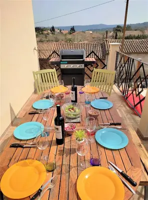 a wooden table with blue plates and wine bottles at VILLA ENTIERE BELLEVUE - Balnéo - Piscine - Clim in Montséret