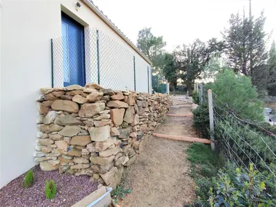 a stone retaining wall next to a building at VILLA ENTIERE BELLEVUE - Balnéo - Piscine - Clim in Montséret