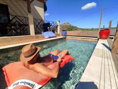 a man laying on a chair in a swimming pool at VILLA ENTIERE BELLEVUE - Balnéo - Piscine - Clim in Montséret