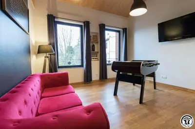 a living room with a red couch and a piano at Les gites du Canal du Midi - Gîte La Cordonnerie in Renneville