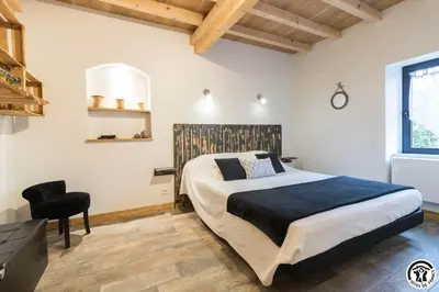 a bedroom with a large bed and a black chair at Les gites du Canal du Midi - Gîte La Cordonnerie in Renneville