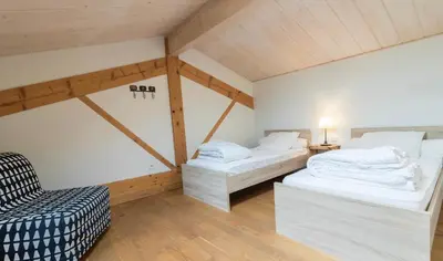 a room with two beds and a chair in it at Les gites du Canal du Midi - Gîte La Cordonnerie in Renneville