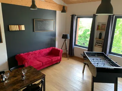 a living room with a red couch and a table at Les gites du Canal du Midi - Gîte La Cordonnerie in Renneville