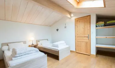 a bedroom with two beds and a wooden door at Les gites du Canal du Midi - Gîte La Cordonnerie in Renneville