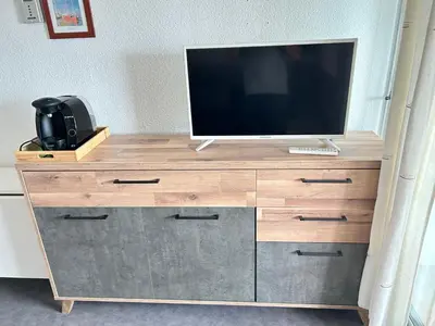 a television on top of a wooden dresser at Appartement vue mer in Gruissan