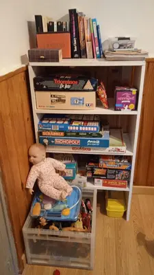 a doll is sitting in a book shelf with books at Repos au vert en Ariège in Le Peyrat