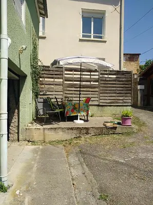 a patio with a fence and an umbrella at Repos au vert en Ariège in Le Peyrat