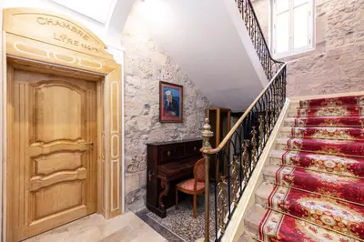 a staircase with a piano next to a stone wall at Suite Impériale Église du Couvent in Narbonne
