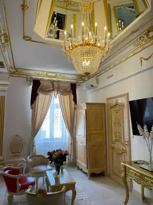 a living room with a chandelier and a table and chairs at Suite Impériale Église du Couvent in Narbonne
