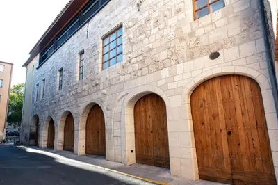 a brick building with four brown wooden garage doors at Suite Impériale Église du Couvent in Narbonne