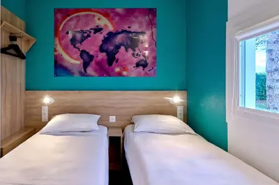two beds in a room with a painting on the wall at Kyriad ECO - Narbonne Sud in Narbonne