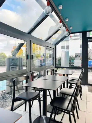 a restaurant with tables and chairs and windows at Kyriad ECO - Narbonne Sud in Narbonne