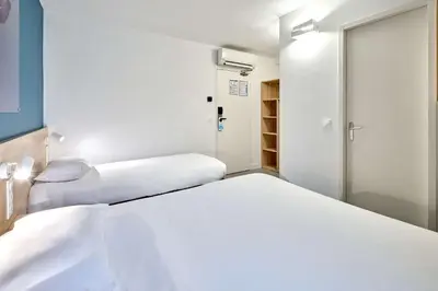 a room with two beds and a closet at Kyriad ECO - Narbonne Sud in Narbonne