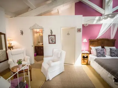 a bedroom with a bed and two white chairs at Chambre d'Hôtes Villa Ambrosia et Spa in Narbonne