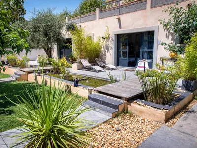a garden with benches and plants in front of a building at Chambre d'Hôtes Villa Ambrosia et Spa in Narbonne