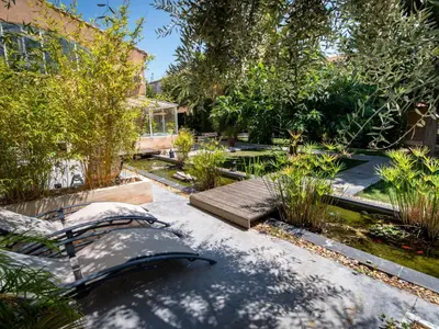 a garden with a bench and trees and a building at Chambre d'Hôtes Villa Ambrosia et Spa in Narbonne