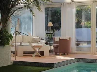 a living room with a couch and a chair and a pool at Chambre d'Hôtes Villa Ambrosia et Spa in Narbonne
